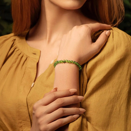 Karma and Luck Peridot August Birthstone Bracelet lifestyle detail — vivid olive-green peridot beads with gold evil eye charm worn elegantly | Bliss by Cori