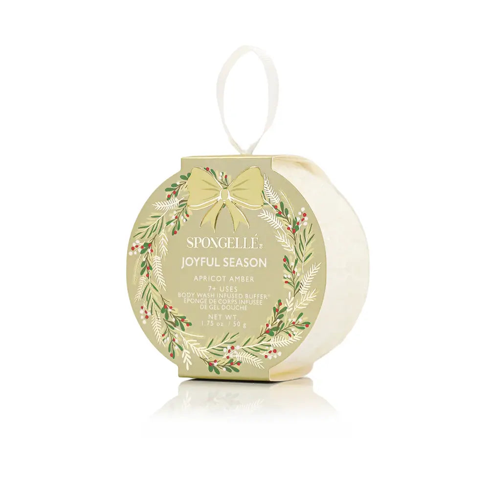 Spongellé Joyful Season Apricot Amber body wash infused buffer in gold ornament-shaped packaging with botanical wreath print on white background — Bliss by Cori Boutique