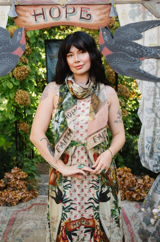 Model wearing Book of Love scarf around her neck over a coordinating floral dress, with printed ends draped in front | Bliss by Cori