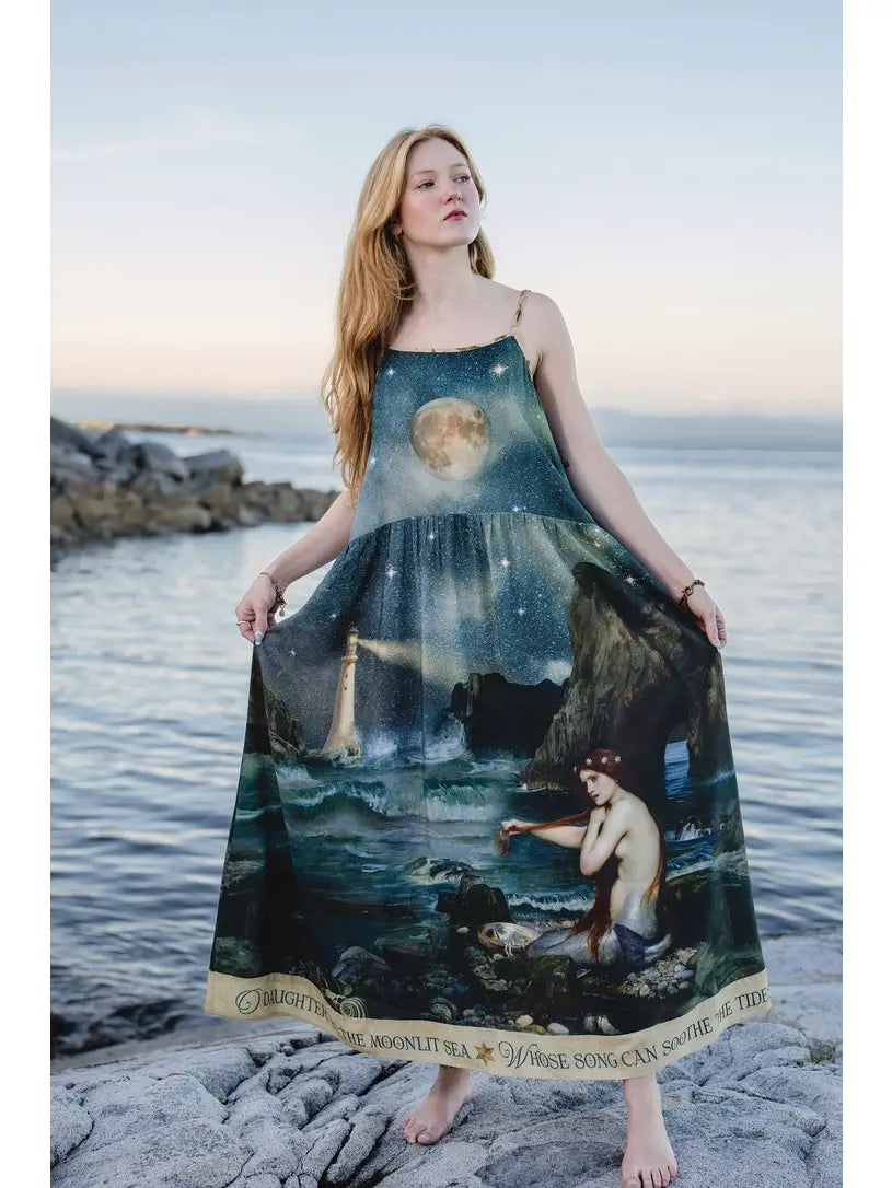 Model holding out the Market of Stars Siren maxi slip dress to show its mermaid and moonlit ocean artwork | Bliss by Cori
