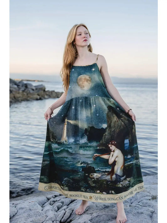 Model holding out the Market of Stars Siren maxi slip dress to show its mermaid and moonlit ocean artwork | Bliss by Cori