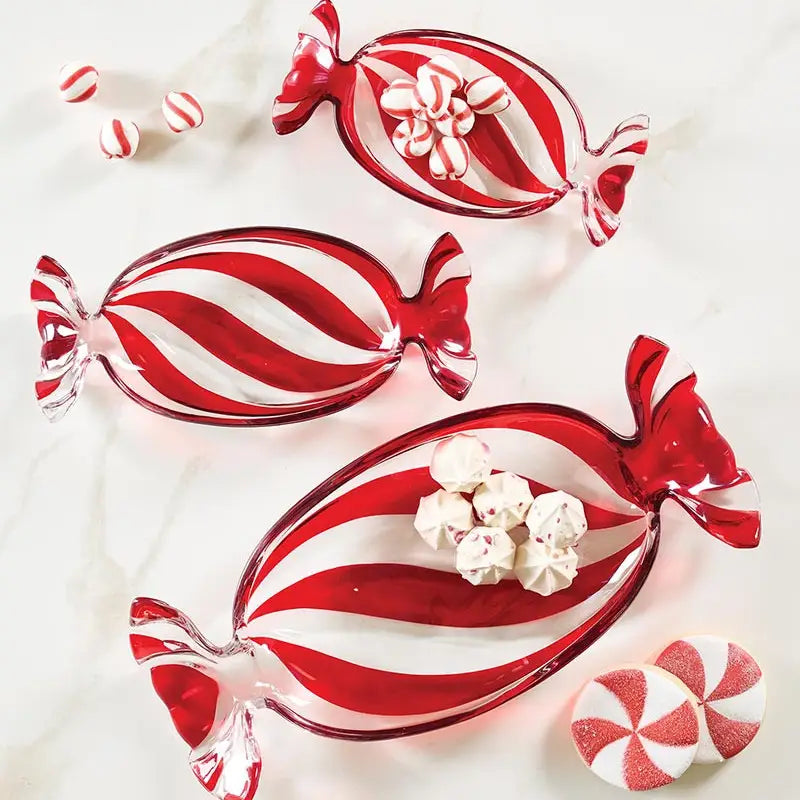 Three red and white peppermint swirl glass candy tray dishes styled on white marble with peppermint candies and white meringue cookies showing large medium and small sizes from the Peppermint Twist collection – Bliss by Cori
