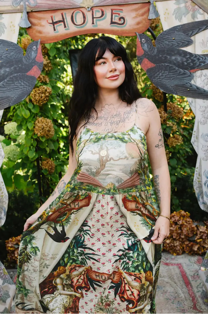 Model holding the Book of Love dress skirt, showing landscape bodice, swallow motifs, and floral artwork | Bliss by Cori