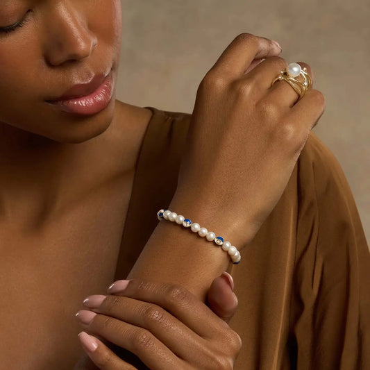 Karma and Luck Blessed Life Evil Eye Pearl Bracelet worn on wrist — lustrous freshwater pearls with navy blue evil eye charms, elegant lifestyle shot | Bliss by Cori