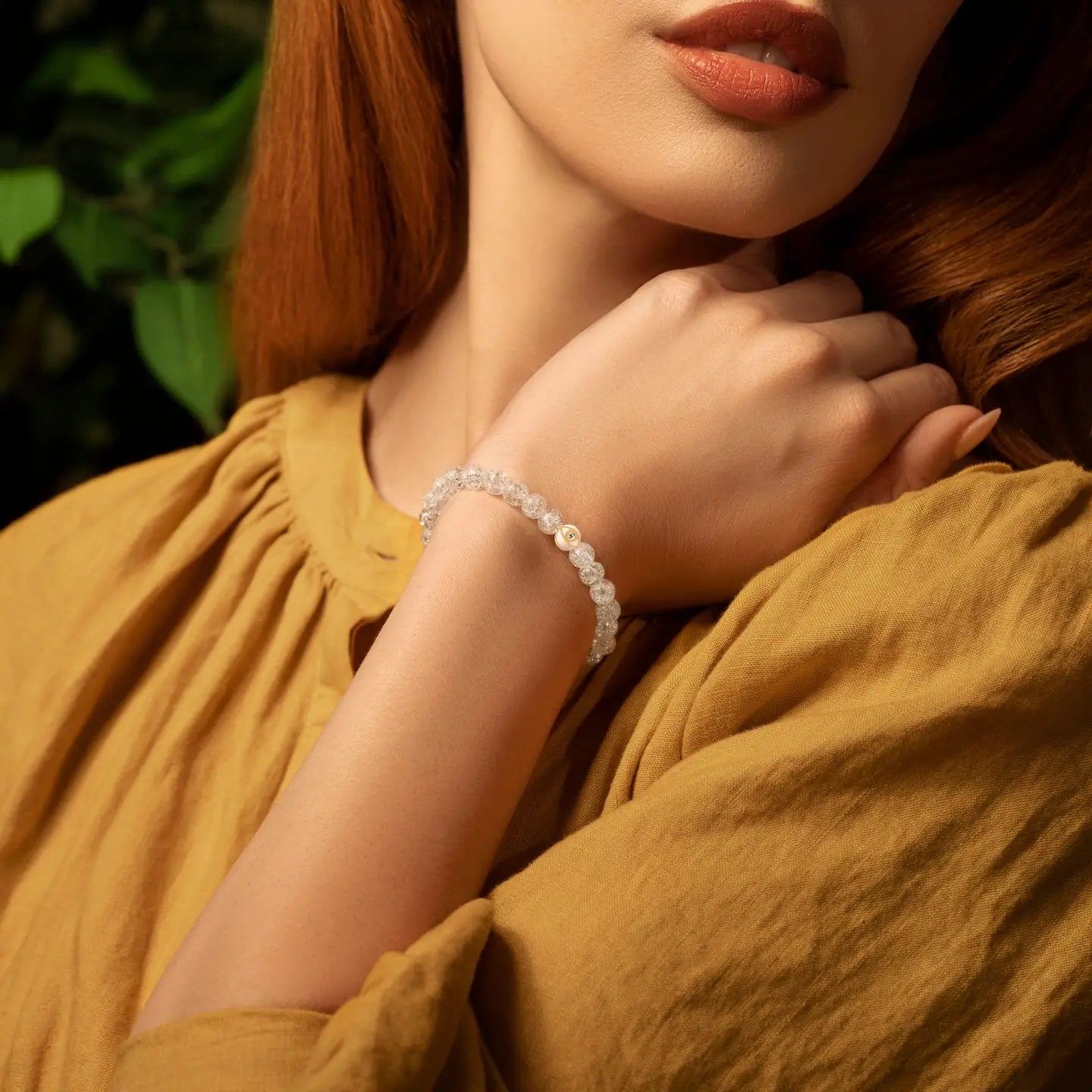 Karma and Luck Utmost Clarity Crystal Quartz Evil Eye Bracelet worn on wrist — crackled clear quartz beads with white and gold evil eye charm, lifestyle shot | Bliss by Cori