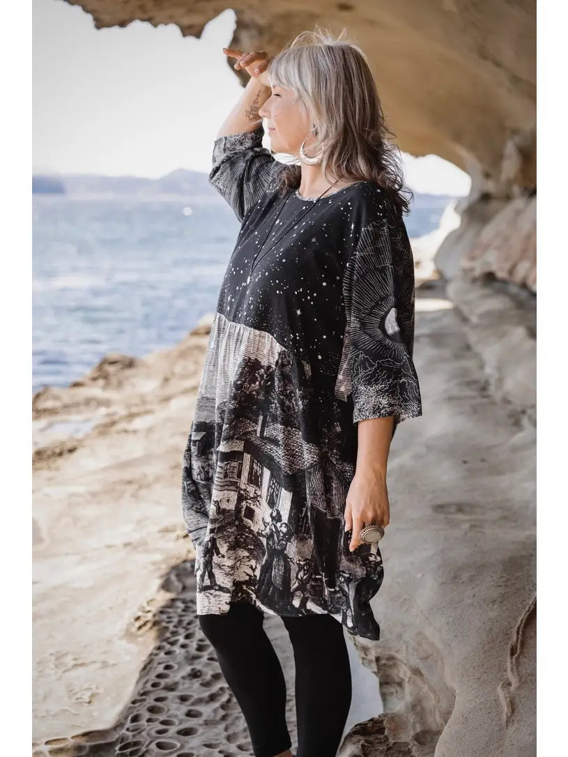 Side view of Stargazer Artist Dress in sandstone cave, woman shielding eyes from sun — celestial print boho shift dress | Bliss by Cori Boutique