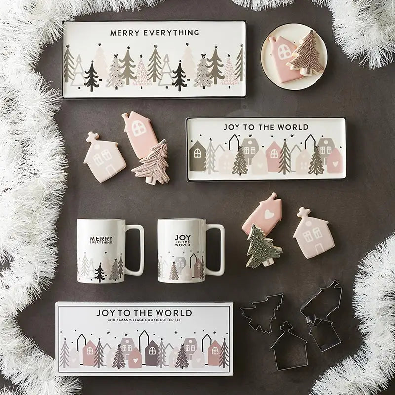 Overhead flat lay of Christmas Village Collection featuring Merry Everything ceramic tray, Joy to the World tray, mugs, cookie cutters and holiday cookies styled with white garland – Bliss by Cori
