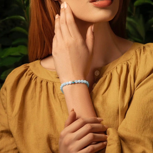 Karma and Luck Soothing Rhythm Aquamarine Evil Eye Bracelet worn on wrist — soft powder blue aquamarine beads with teal evil eye charm, lifestyle shot | Bliss by Cori