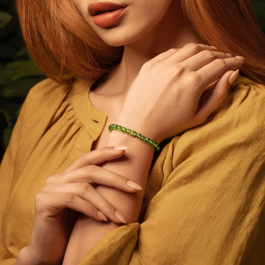 Karma and Luck Peridot Evil Eye Bracelet worn on wrist — natural green peridot gemstone beads with gold evil eye charm, lifestyle shot | Bliss by Cori