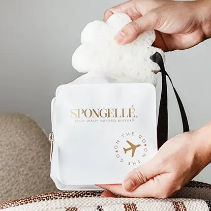 Hands pulling a white Spongellé body buffer out of the white travel case showing easy access zipper — Bliss by Cori Boutique