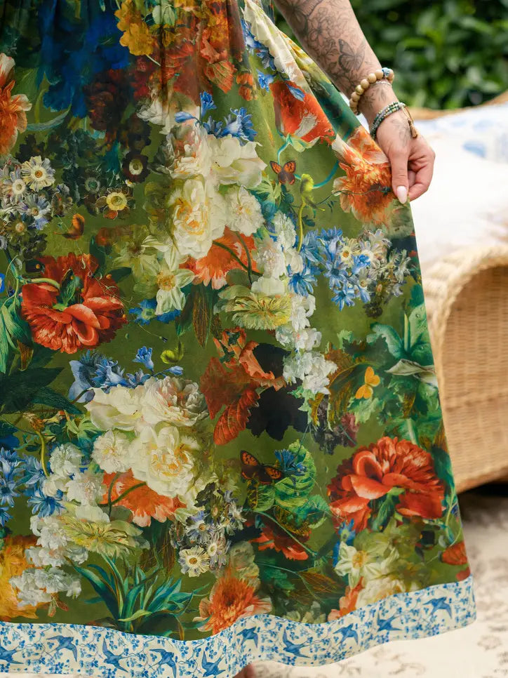 Close-up of green Flora Poetica maxi dress fabric with colorful flowers, birds, and blue floral border trim | Bliss by Cori