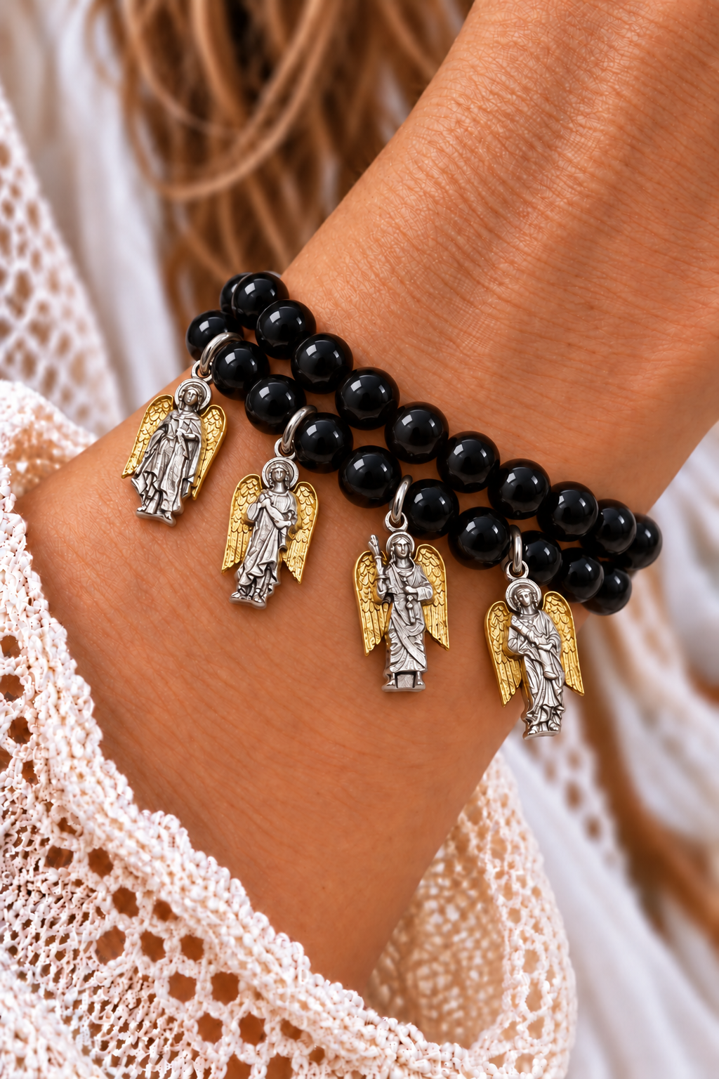 Two black tourmaline bead bracelets with four silver-tone archangel charms and gold-tone wings worn on a wrist | Bliss by Cori