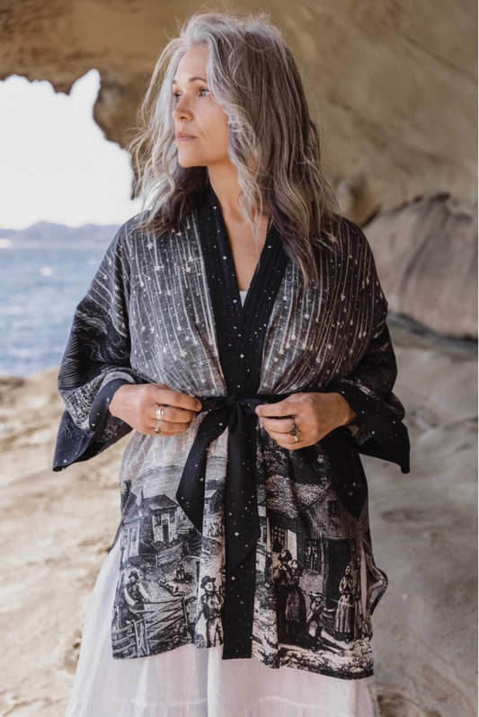 Stargazer Matineé Duster celestial print kimono worn by woman gazing at ocean from rocky coastal cliffs — boho-luxe style | Bliss by Cori Boutique