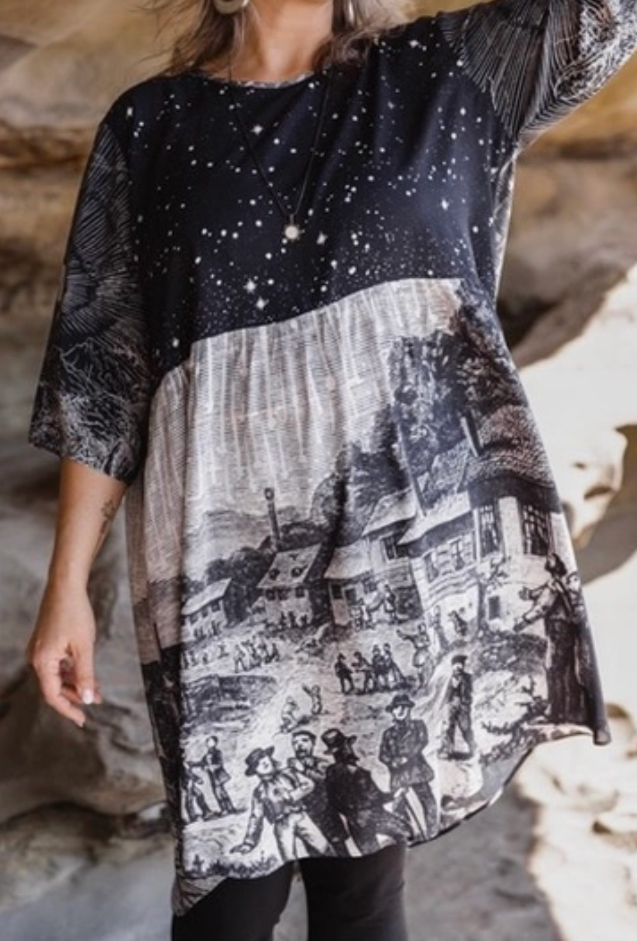 Woman in Stargazer Artist Dress seated on coastal rocks gazing at ocean — relaxed shift silhouette with celestial print | Bliss by Cori Boutique
