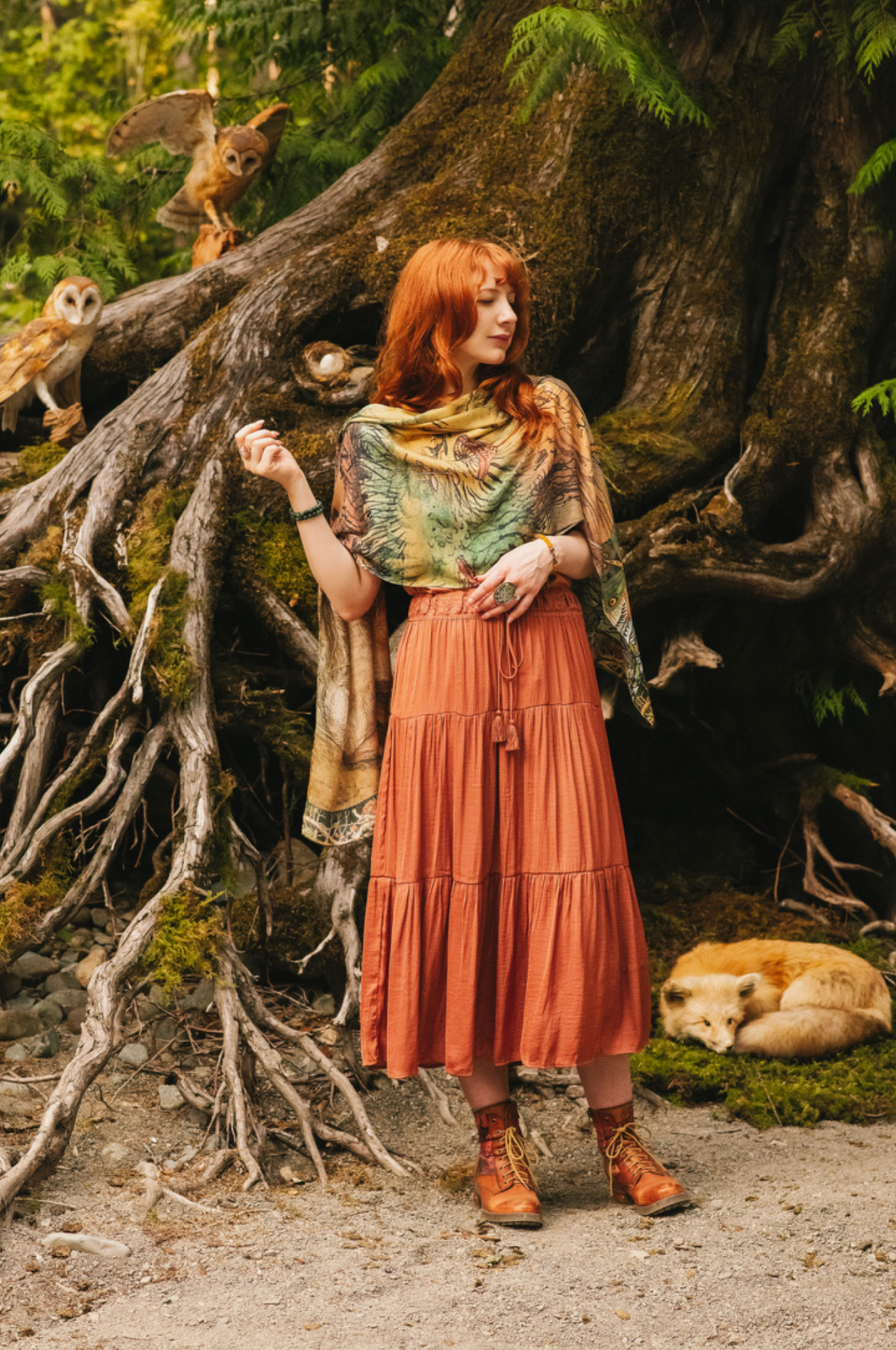 Model wearing Woodland Wisdom Bohemian Scarf belted as a wrap dress over a rust skirt, large rabbit print visible on front, owls and sleeping fox in enchanted forest background — Bliss by Cori