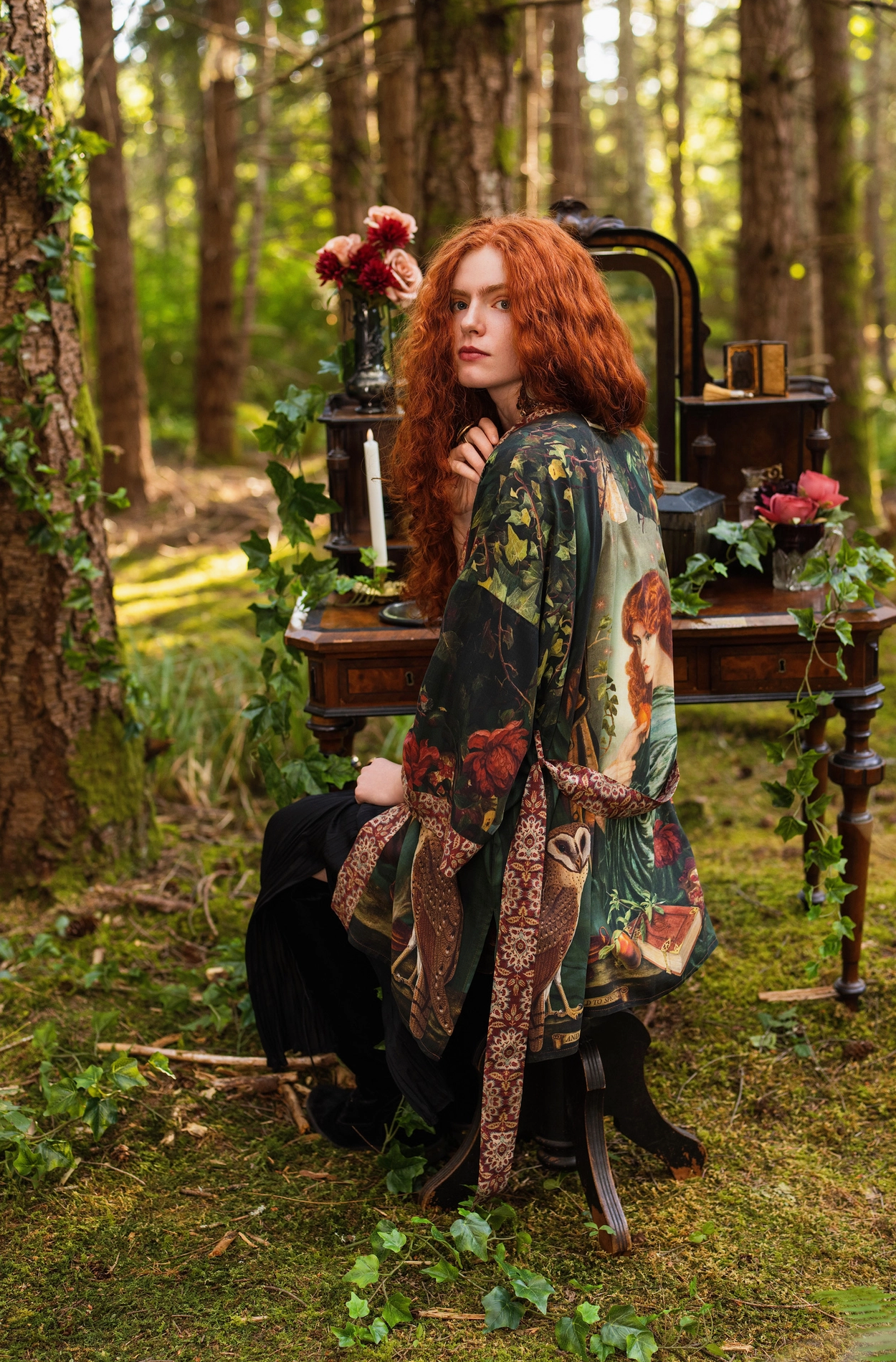 Back view of red-haired model in forest reading a book wearing Solstice Matinée Mid-Length Duster Kimono, full Rossetti Proserpine print visible on back, barn owl perched above, enchanted outdoor bedroom setting — Bliss by Cori