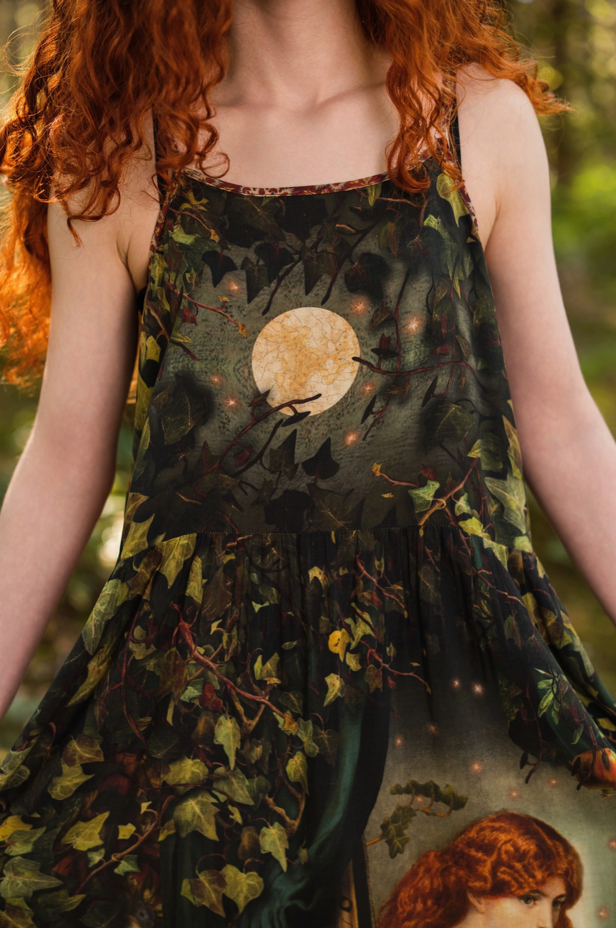 Close-up of red-haired model wearing Solstice Bohéme Maxi Slip Dress showing moon and trailing ivy bodice print with lace neckline detail, sunlit forest background — Bliss by Cori