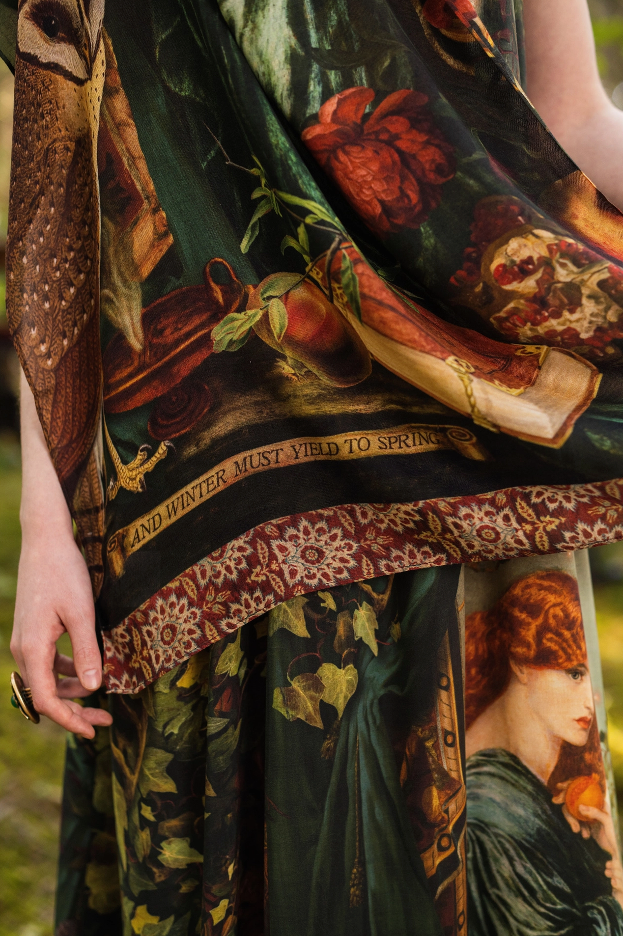 Close-up detail of Solstice Bohemian Scarf showing barn owl, antique book, pomegranate, roses and "and winter must yield to spring" gold banner inscription with terracotta tapestry border on dark green viscose — Bliss by Cori