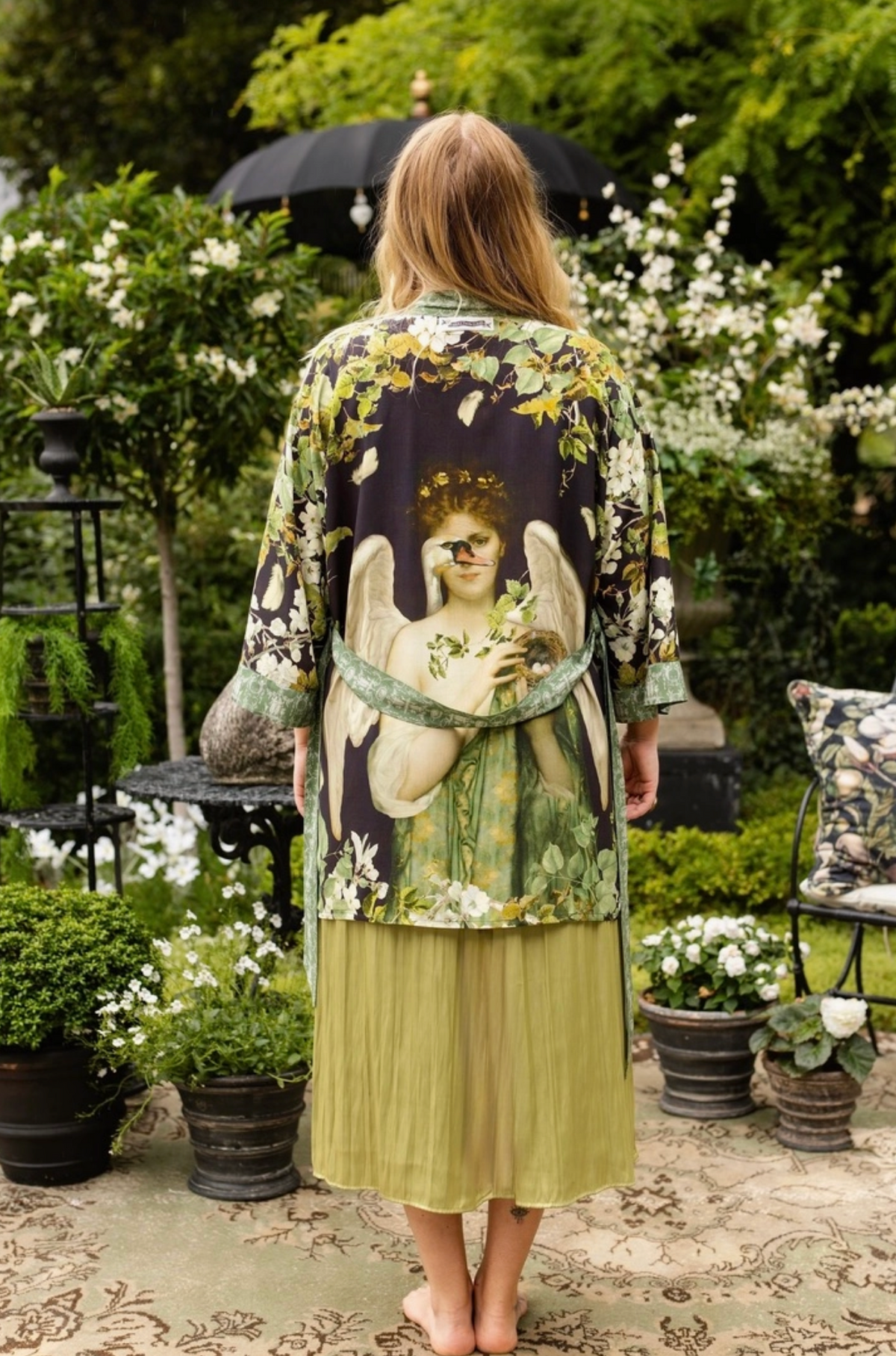 Rear garden view showing the flowing mid-length fit and statement back artwork of the Equinox duster | Bliss by Cori