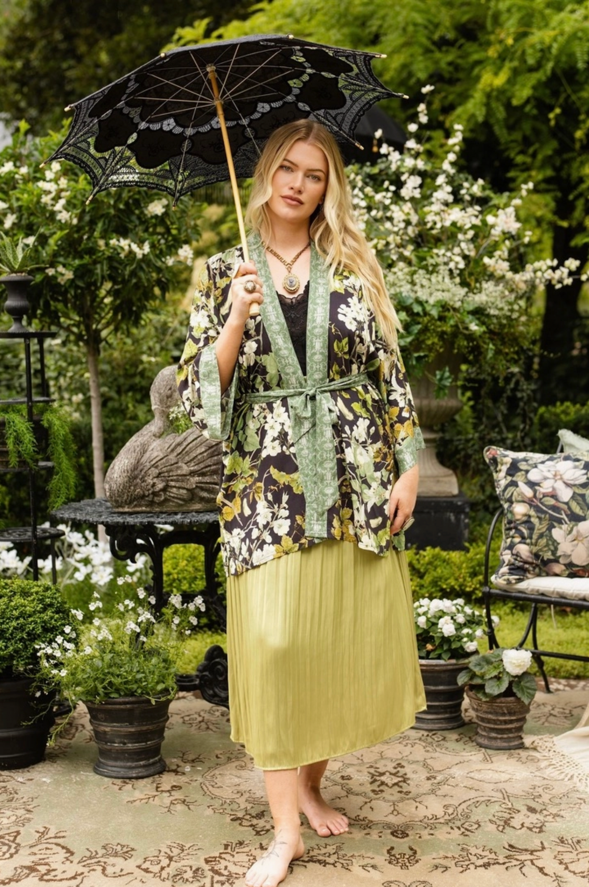 Model wearing the Equinox duster with a black parasol among flowers and greenery | Bliss by Cori