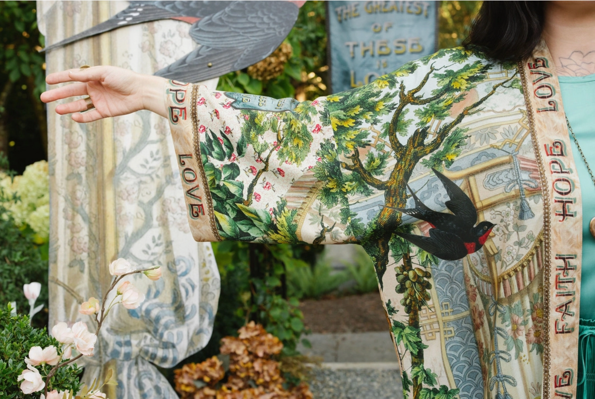 Front sleeve detail of Book of Love duster showing a black swallow, leafy branches, and lettered trim | Bliss by Cori
