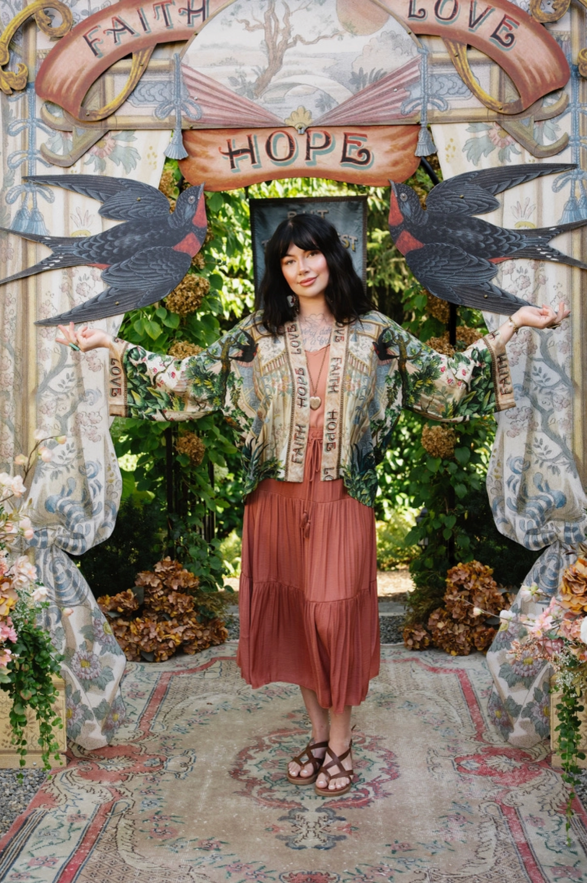 Model wearing Book of Love cropped kimono over a coral dress with arms extended to show its wide sleeves | Bliss by Cori