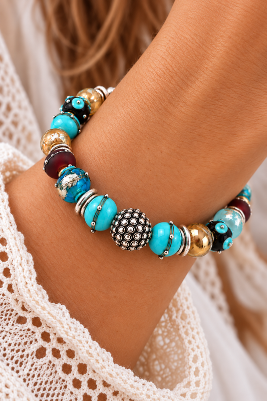 By the Bay bracelet worn on a wrist, featuring turquoise, aqua and brown lampwork glass beads with silver accents and a decorative silver-tone center bead | Bliss by Cori