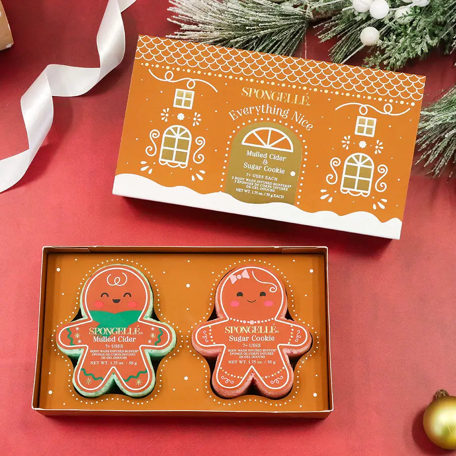 Spongellé Everything Nice gift set open box with gingerbread buffers on red holiday background with pine branches and gold ornament — Bliss by Cori Boutique