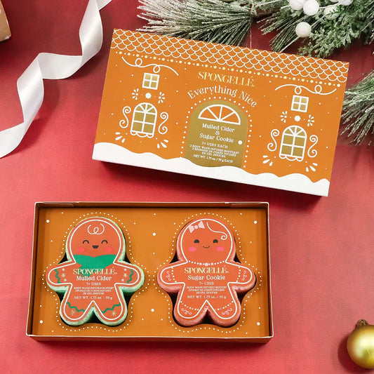 Spongellé Everything Nice gift set open box with gingerbread buffers on red holiday background with pine branches and gold ornament — Bliss by Cori Boutique