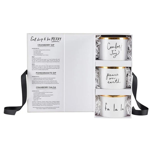 Eat Dip & Be Merry holiday dip bowl gift set open showing three white ceramic bowls with gold rims reading Comfort + Joy, Peace on Earth and Fa La La nestled in white paper shred with dip recipe card – Bliss by Cori
