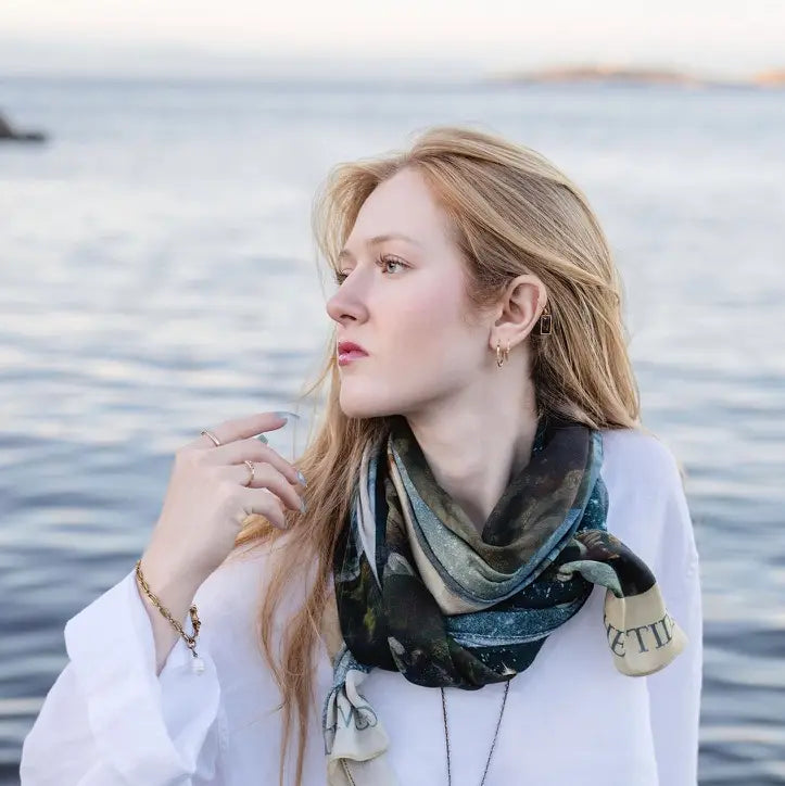 Front close-up of the Siren celestial scarf styled over a white top beside the water | Bliss by Cori