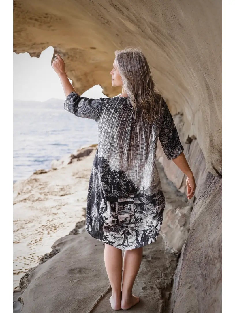 Back view of Stargazer Artist Dress in sandstone cave showing Leonid meteor shower print on back, barefoot on coastal rocks | Bliss by Cori Boutique