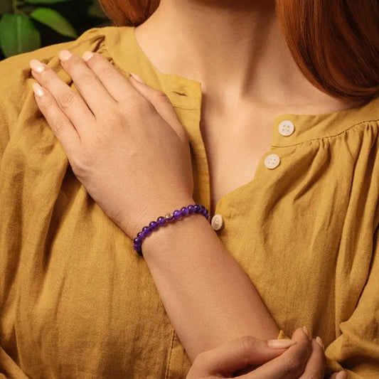Karma and Luck Calming Reflection Amethyst Evil Eye Bracelet worn on wrist — deep violet amethyst beads with gold evil eye charm, lifestyle shot | Bliss by Cori