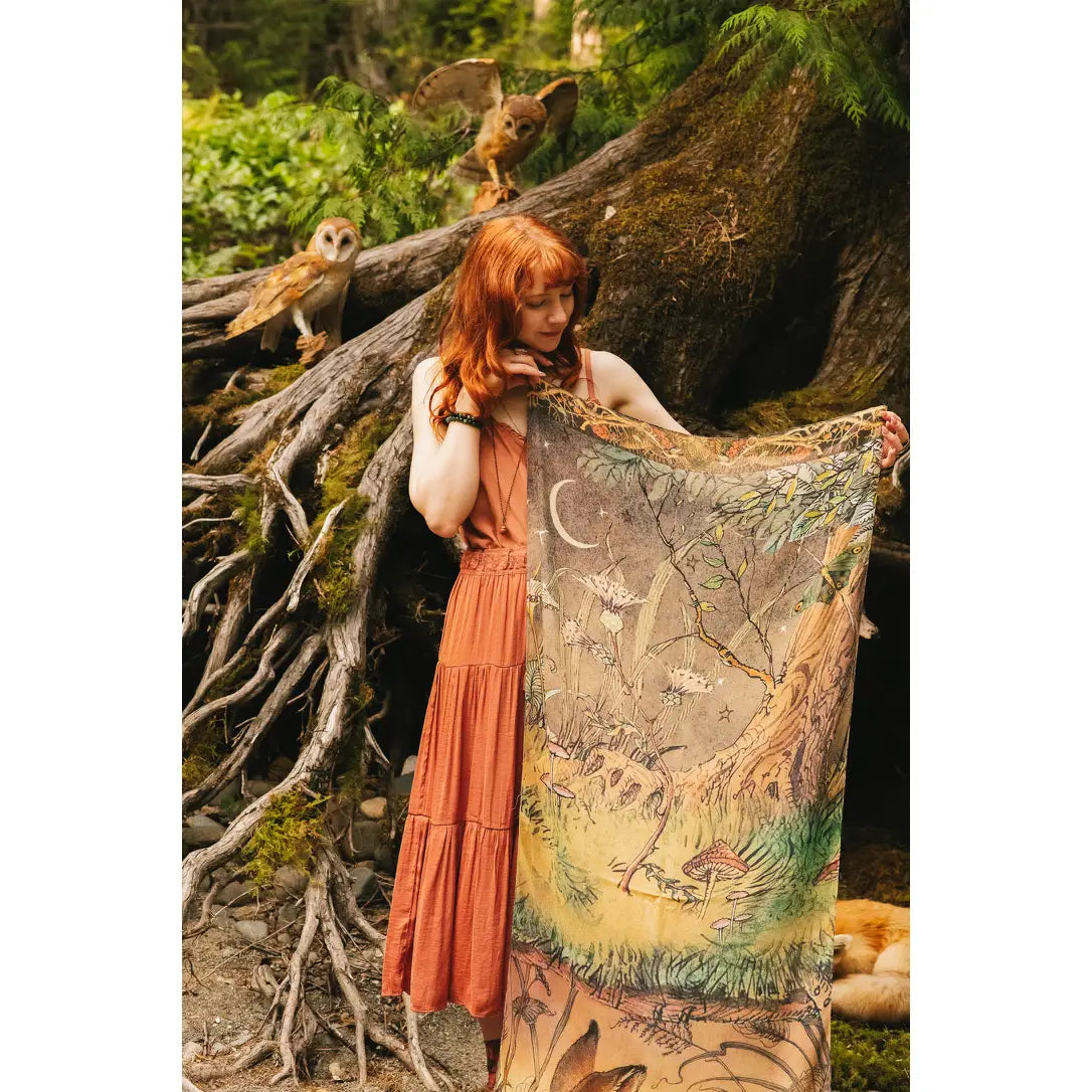 Model holding Woodland Wisdom Bohemian Scarf open to display the full moonlit forest scene with mushrooms, crescent moon, branches and woodland creatures, owls perched on ancient tree roots — Bliss by Cori