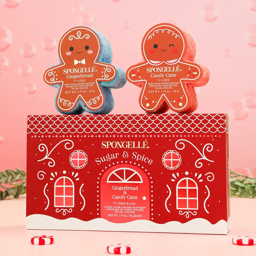 Spongellé Sugar & Spice gingerbread body buffers propped on red gift box with candy cane accents and pink background — Bliss by Cori Boutique