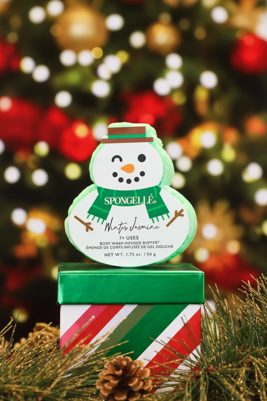 Spongellé Winter Jasmine snowman body buffer in cozy holiday lifestyle scene with Christmas tree bokeh lights — Bliss by Cori Boutique