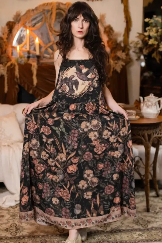 Momento Bohème Maxi Slip Dress in dark floral print with raven and rose motif, worn by woman in moody vintage interior setting — boho-luxe maxi dress | Bliss by Cori Boutique